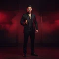 Malay man standing in red and black cinematic lighting, holding perfume confidently, strong masculine mood