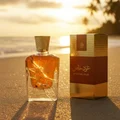 Perfume bottle broken, amber glow emerging; Langkawi beach at sunset Malaysia — clear bottle and box, cinematic lighting