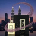 Kayaan Gold with plum vapor spiral and ozonic bubbles on reflective black, KL skyline dusk; bottle and box clearly visible