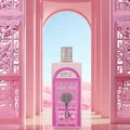 Pink perfume bottle with decorative cap in front of a pink archway