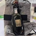 Bottle of Mousf with a gold label held by a person wearing a textured garment.