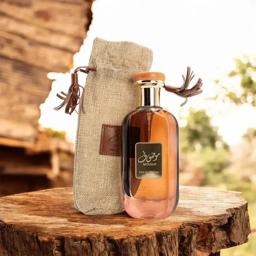 Perfume bottle with a fabric pouch on a wooden surface outdoors