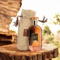 Perfume bottle with a fabric pouch on a wooden surface outdoors