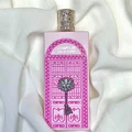 Perfume bottle with pink packaging featuring decorative elements on a white fabric background