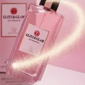 Glitz & Glam floating above mirror with vanilla stardust comet tail; soft pink glow; bottle and box clearly visible.