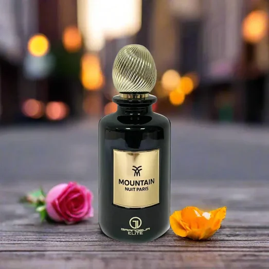 Perfume bottle labeled 'Mountain Nuit Paris' with flowers on a wooden surface