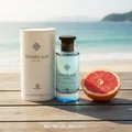 Men's perfume bottle and box on beach wood table in with grapefruit slice and ocean view – summer fresh fragrance