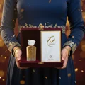 Malaysian woman reveals Sham Perfume Woman — Gulf Orchid bottle and box from a velvet gift; warm spotlight, clear product.