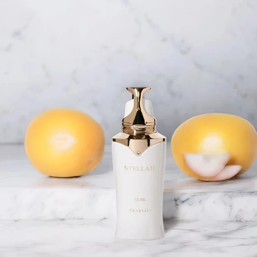 White skincare bottle with gold cap on a marble surface with two yellow fruits
