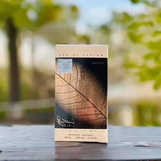 Lattafa Najdia in Gold eau de parfum box on a wooden surface with a blurred natural background