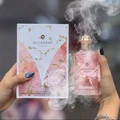 Pink 'Decadent' perfume bottle and packaging held by a person with a blurred background