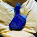 Blue bottle labeled 'LUXE' on a beige fabric background