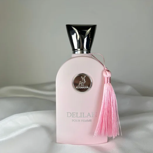 Pink perfume bottle with a tassel on a white fabric background