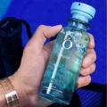 Hand holding a blue bottle with a brand logo against a blue background