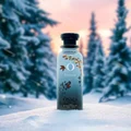 Bottle of Osmia Bonsai in a snowy landscape with trees in the background