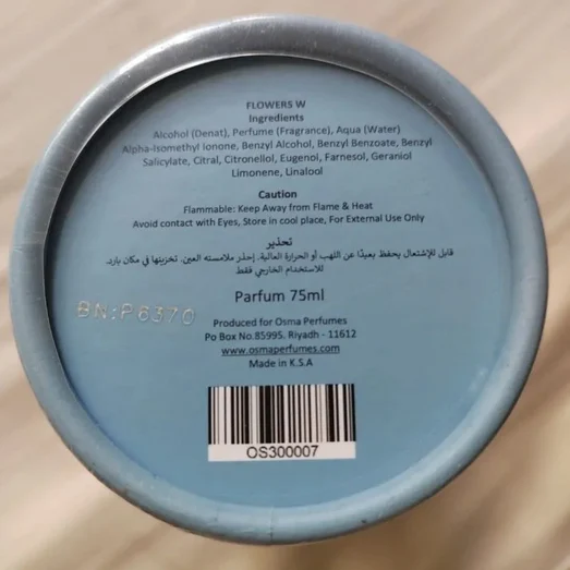 Back of a perfume container with text and barcode on a beige surface