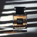 Perfume bottle labeled 'Club Intense' by Pendora on a dark surface with shadow patterns