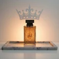 Al Embratur Elixir botol centered on marble tray with amber light from behind; subtle crown shadow cast on wall Malaysia