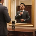 Malay man adjusting tie with oud is great by Zimaya perfume on dresser modern luxury men fragrance