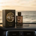 Reverie Aqua by Zimaya perfume bottle on car dashboard with ocean view fresh men fragrance