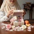 Malay hijabi woman receiving perfume gift box on table with rose petals – Rose of Dreams