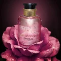Perfume bottle labeled 'Rose of Dreams zimaya' on a pink rose with water droplets