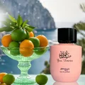 Pink Zimaya eau de parfum bottle with a bowl of oranges and limes against a scenic background